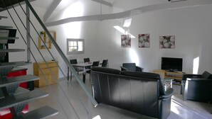 A modern living room with a staircase, a dining area, and a TV. - Country house at the gateway to the Limousin-Périgord nature park. (Rilhac-Lastours)