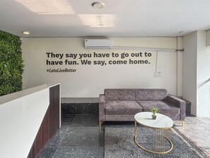 A modern lobby with a grey sofa, a small round table with a plant, and a motivational quote on the wall. - Housr Sector 28 Golf Course Road Next To Phase 1 Metro Station (Gurugram)