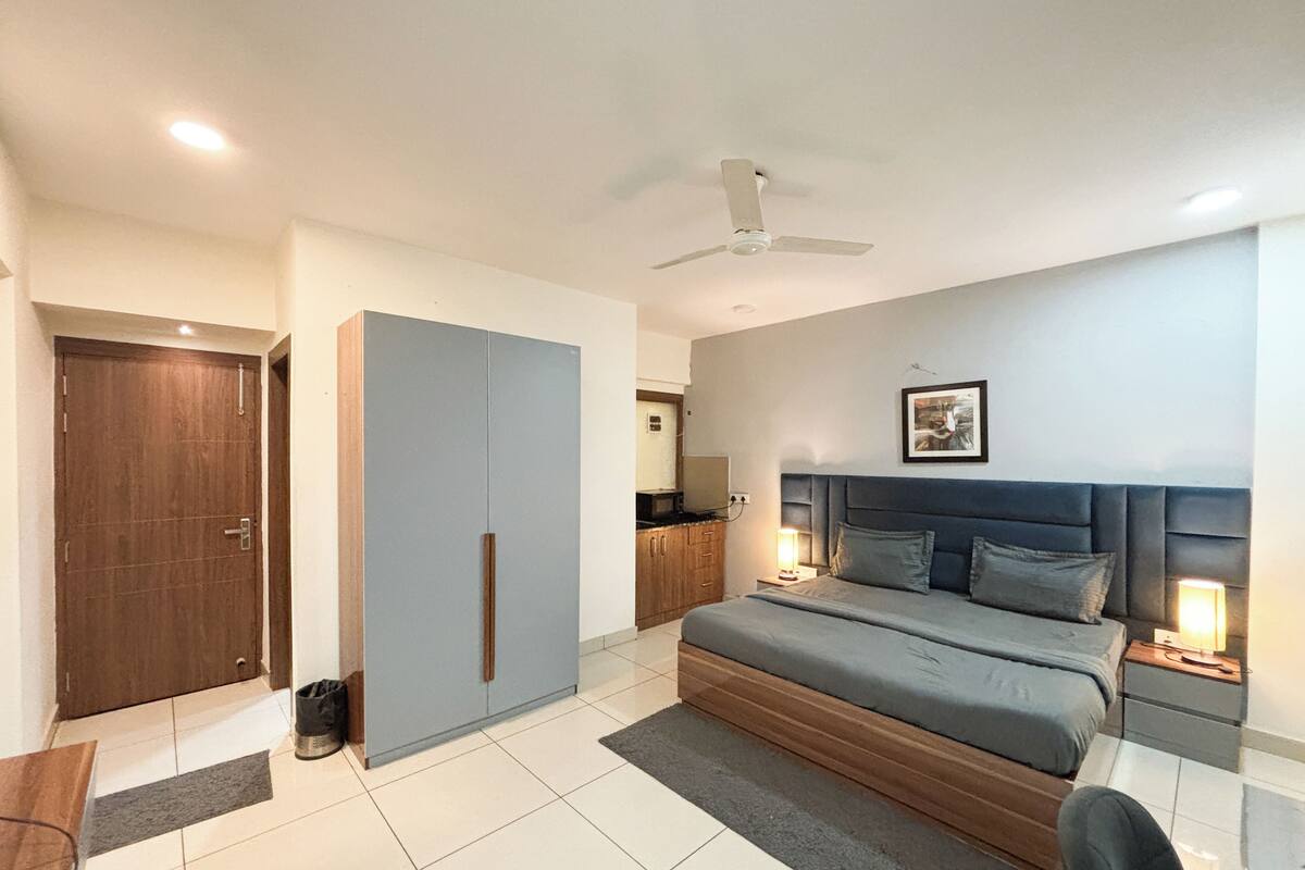 Un dormitorio con cama, armario, escritorio y ventilador de techo.