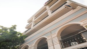 Un edificio de varios pisos con un letrero llamativo en la parte superior, ventanas grandes y balcones con barandillas de metal.