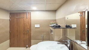 Un baño con puerta de madera, un lavamanos blanco, un espejo y un perchero para toallas.
