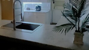 A kitchen with white cabinets, a sink, a countertop, and a ceiling fan.