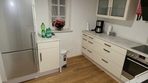 A kitchen with a stainless steel refrigerator, a coffee maker, and a trash bin. - Pension Kostera, 1st Floor | 7 single beds & parking (Babenhausen)