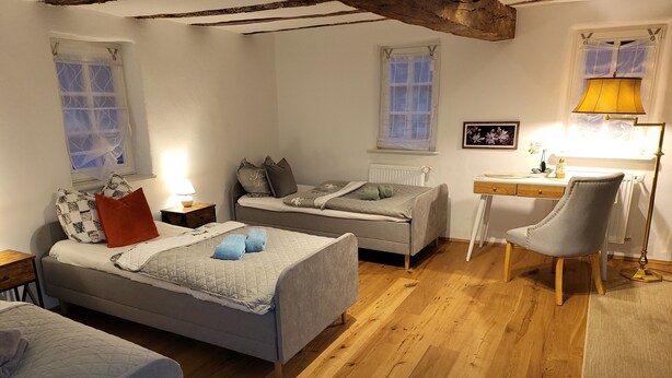 A cozy bedroom with two beds, a desk, and a chair. - Pension Kostera, 1st Floor | 7 single beds & parking (Babenhausen)