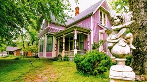 Une maison historique dotée d’un porche, d’une statue et d’un chemin en briques.