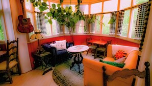 Une pièce agréable et intime, avec une fenêtre en arc de cercle, une guitare, une table et un canapé.