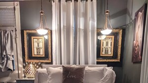 Une chambre à coucher avec un grand lit, deux lampes fixées au mur et un tableau encadré accroché au mur.
