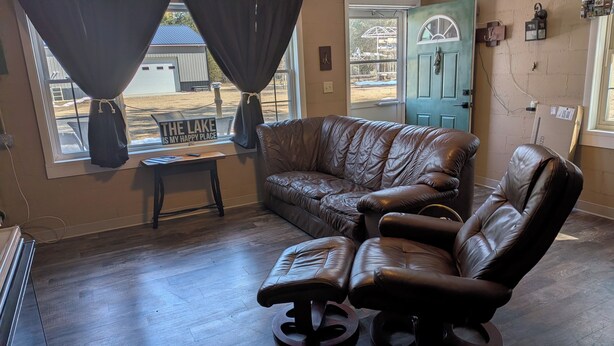 A room with a leather sofa, a small table, a view of a building outside, and a door with a sign.