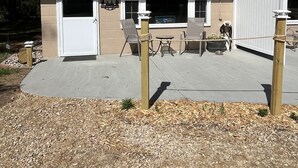 A single-story building with a beige exterior and a green roof. There is a covered patio area with outdoor seating.