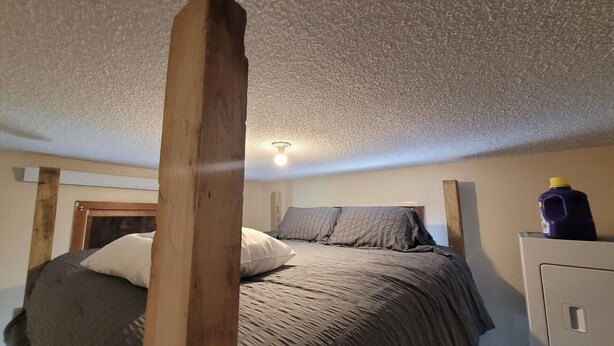 Ein Schlafzimmer mit einem Bett, einem hölzernen Kopfteil, einem Nachttisch und einem Wandheizkörper.