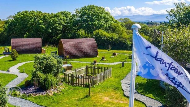 Ein Campingplatz mit zwei kuppelartigen Hütten, einer Flagge und einem eingezäunten Bereich mit einem Picknicktisch.