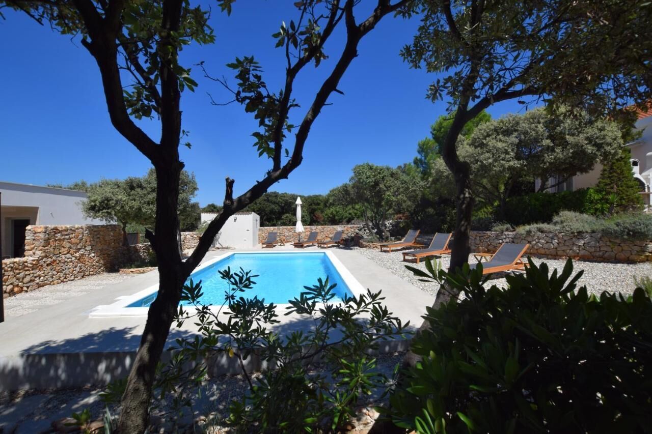 A swimming pool with lounge chairs and a stone wall.