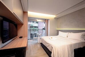 A hotel room with a bed, a TV, a small table, and a balcony with a view. - JAUAPERI 207 (Indianópolis São Paulo)