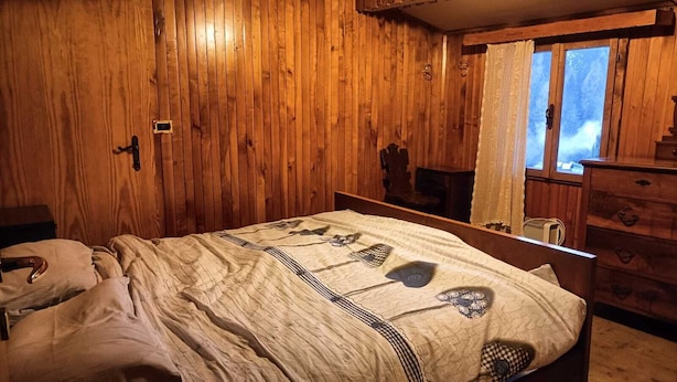 Una habitación de madera con una cama, un aparador y una ventana.