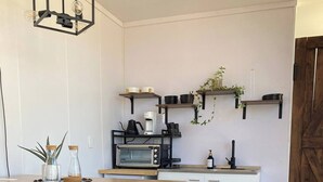 Une cuisine moderne dotée d’un îlot central, de tabourets de bar, d’un four à micro-ondes, d’une machine à café et de plantes suspendues.