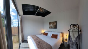 Une chambre moderne avec un grand lit, une vue sur l’extérieur, un tableau au mur et un porte-serviettes.