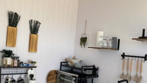 Une cuisine compacte avec des meubles blancs, un plan de travail en bois, un grille-pain encastré et un porte-ustensiles suspendu.