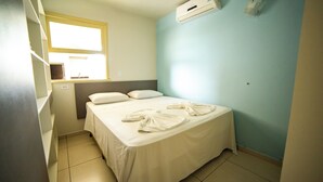 Un dormitorio pequeño y ordenado, con cama, almohadas y una ventana.