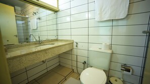 A bathroom with a sink, mirror, toilet, and towel rack.