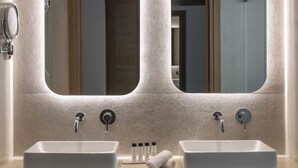 A bathroom with two sinks, each with a mirror above. There are towels and toiletries on the counter. - Arocaria Hotel (Mykonos)