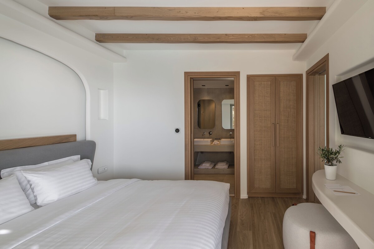 A bedroom with a bed, a built-in wardrobe, a mirror, and a television.