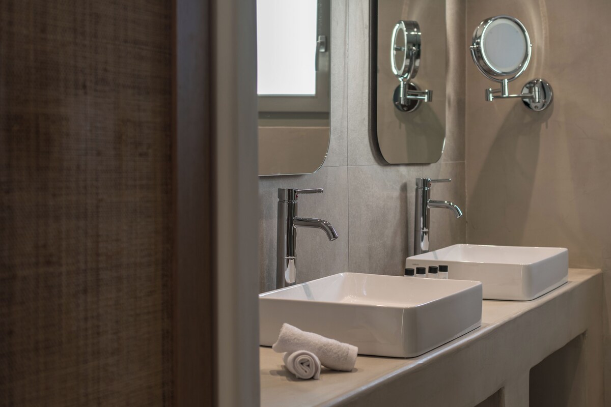 Un bagno moderno con due lavandini, uno specchio e un asciugamano sul ripiano.
