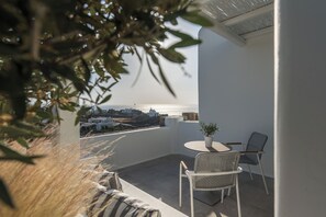 En balkon med havudsigt, et bord med stole og en potteplante.