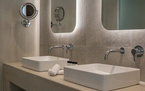 A bathroom with two white sinks, a towel, and a mirror. - Arocaria Hotel (Mykonos)