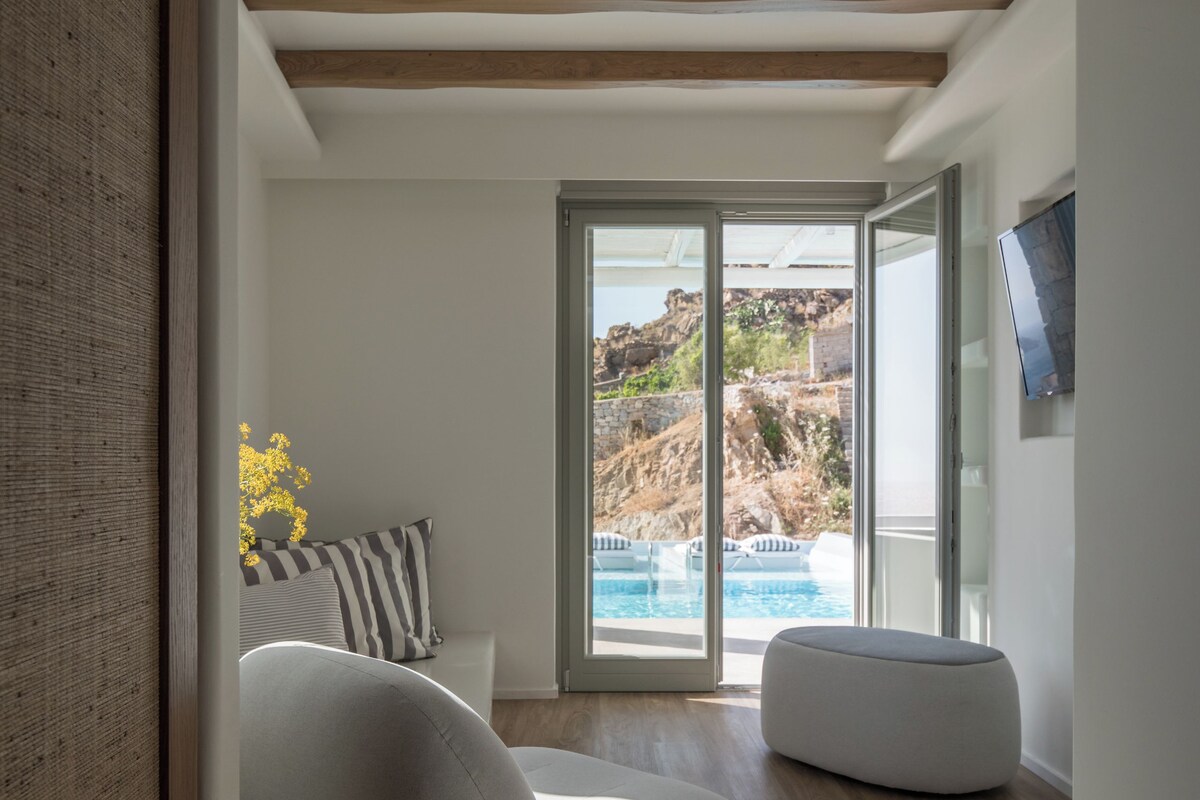 A modern living room with a view of a pool and mountains.