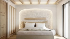 Une chambre moderne avec un grand lit, un mur texturé derrière le lit, des poutres en bois au plafond et une grande fenêtre sur le côté droit.