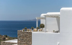 Un edificio blanco con muro de piedra y vista al mar.