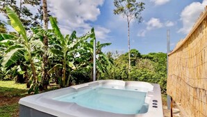 A hot tub in an outdoor setting with a bamboo fence and lush greenery in the background. - Private Eco-Luxury Villa near Rio Celeste | Jacuzzi • Nature • Sleeps 8 • (El Higueron de Upala)