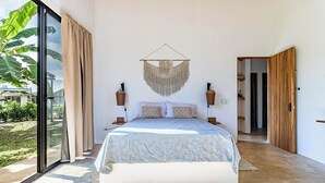 A spacious bedroom with a large bed, a hanging macrame piece, and a view of the outdoors. - Private Eco-Luxury Villa near Rio Celeste | Jacuzzi • Nature • Sleeps 8 • (El Higueron de Upala)