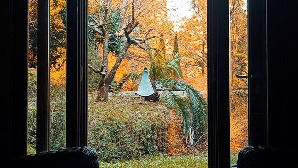 Obertura a un jardí amb vistes a arbres d'autorriu, una cadira espanyola i dos sofàs de vimetla amb coixins.