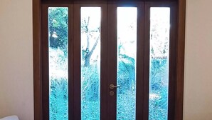Una habitació amb dos sofàs de vímet, una catifes amb dibuixos i una porta que dona a un jardí.