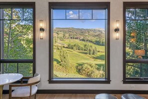 A room with a large window offering a view of a golf course and hills. - Vista Haus at Country Club - golf and ski retreat! (Mountain Village)
