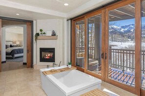 A modern bathroom with a bathtub, a fireplace, and a view of a snowy mountain landscape through large sliding glass doors. - Vista Haus at Country Club - golf and ski retreat! (Mountain Village)
