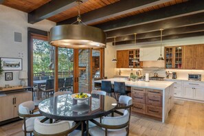 A modern kitchen with a central island, wooden cabinets, and a dining area with a glass table and chairs.