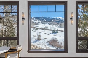 A room with a large window offering a view of a snowy landscape with mountains.