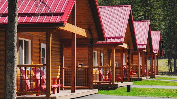 A row of log cabins with red roofs and wooden porches.