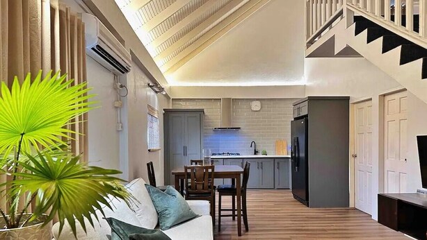 Amplia sala de estar con un sofá, una mesa de comedor y una cocina al fondo.