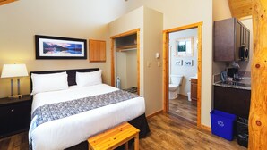 A bedroom with a bed, bedside table, and a view of the bathroom.