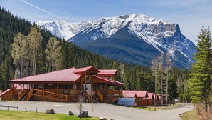 A lodge with a red roof, a covered porch, and a view of snow-capped mountains.