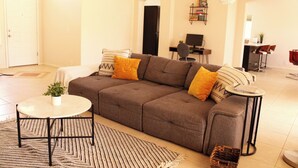 Ein Wohnzimmer mit einer Couch, einem kleinen runden Tisch, einem gemusterten Teppich und einem Bücherregal.