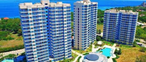 A high-rise hotel complex with multiple floors, a swimming pool, and a tennis court.