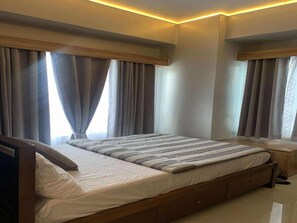 A modern bedroom with a large bed, wooden headboard, and curtains.