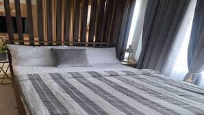 Ein ordentlich bezogenes Bett mit Streifenmuster, ein Holzkopfschild und ein Nachttisch mit Lampe.
