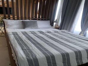 A neatly made bed with striped bedding, a wooden headboard, and a nightstand with a lamp.
