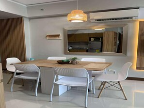 A modern dining area with a wooden table, white chairs, and a large mirror above.