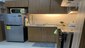 Una cocina con refrigerador de acero inoxidable, gabinetes de madera, microondas y un lavamanos.